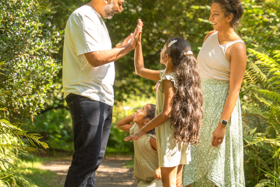 Father and daughters doing a high five with their hands.