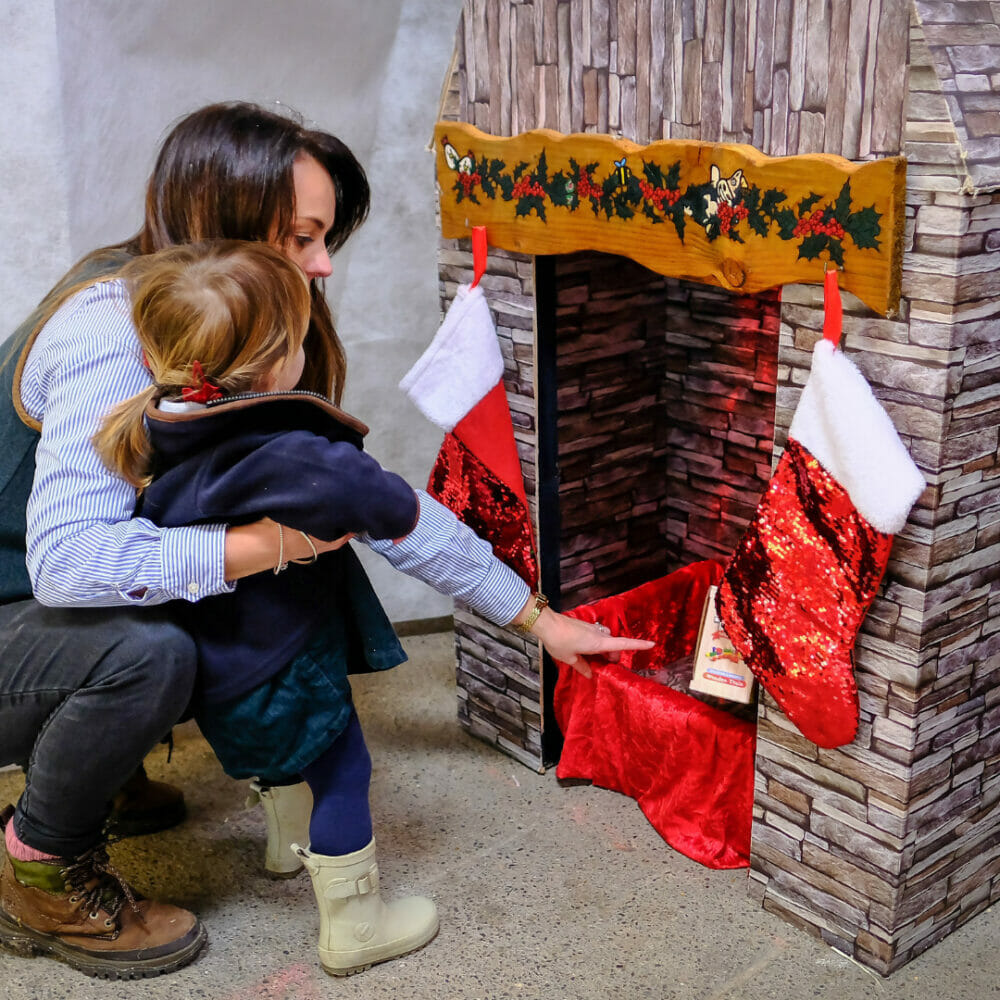 mother and child waiting at a chimney for present Farmer Christmas at Farmer Palmers