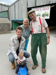 4 generations of father, son, father and daughter with baby on little tractor
